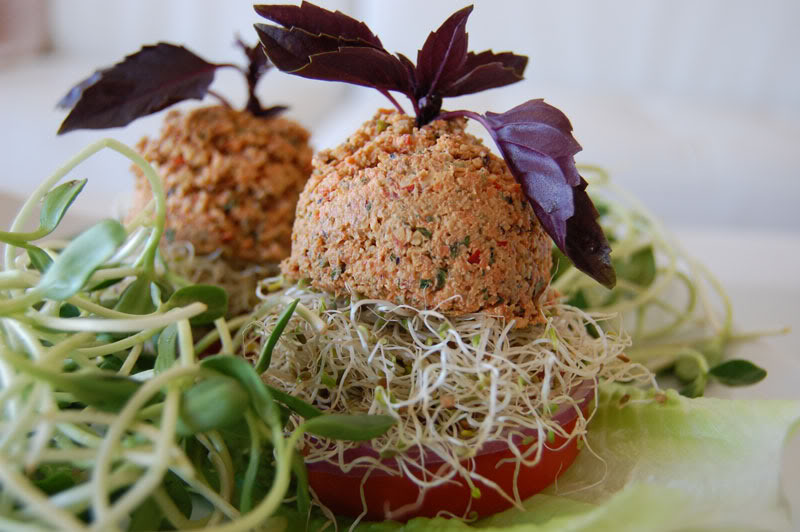 The Global Girl Raw Food Recipes: Raw Vegan Burger with a walnut patty and avocado, clover and sunflower sprouts in a tomato bun. This raw veggie burger is gluten free and oil free.