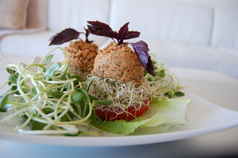 The Global Girl Raw Food Recipes: Raw Vegan Burger with a walnut patty and avocado, clover and sunflower sprouts in a tomato bun. This raw veggie burger is gluten free and oil free.