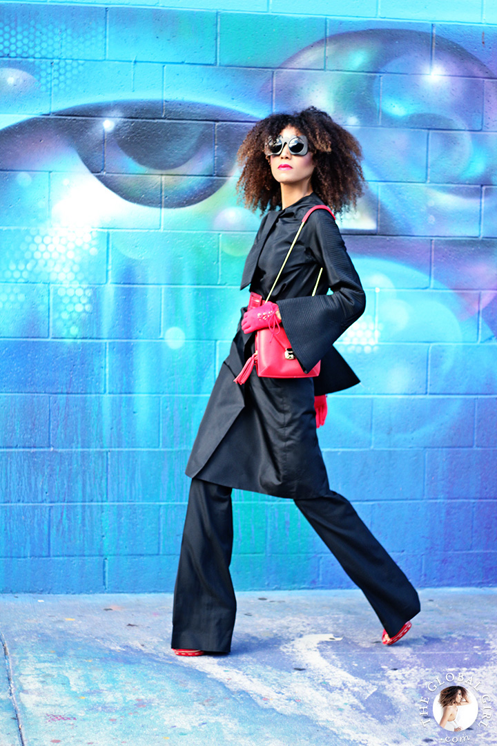 Ndoema dons a vintage silk coat and Balenciaga flare pants with Le Specs Craig and Karl x Le Specs ‘Lost Weekend’ sunglasses, Miu Miu red patent leather pumps, red patent leather belt by Betsey Johnson, Onna Ehrlich red crossbody bag and vintage red gloves. 