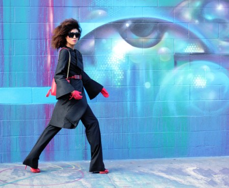 Ndoema dons a vintage silk coat and Balenciaga flare pants with Le Specs Craig and Karl x Le Specs ‘Lost Weekend’ sunglasses, Miu Miu red patent leather pumps, red patent leather belt by Betsey Johnson, Onna Ehrlich red crossbody bag and vintage red gloves.