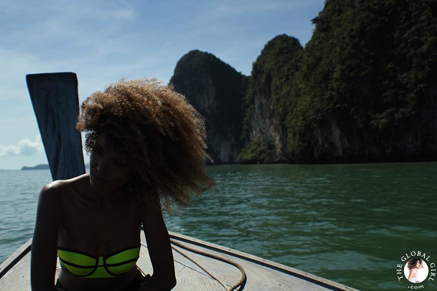 The Global Girl Travels: Ndoema sports a contrast neon bikini with mirrored aviator sunglasses while sailing off James Bond Island in Phang Nga Bay, Thailand.