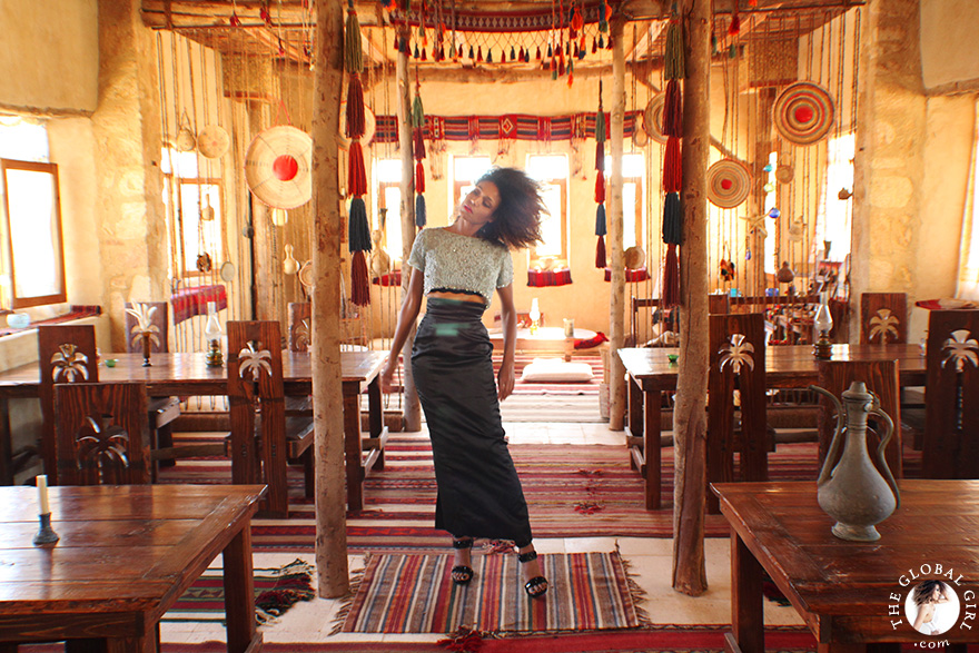 The Global Girl Travels: Ndoema at Talist, a Berber-style luxury and eco-friendly resort at Siwa Oasis, Egypt. Ndoema sports a high-waist maxi skirt by Vivienne Westwood with a vintage embellished cropped top and jeweled stiletto heels.