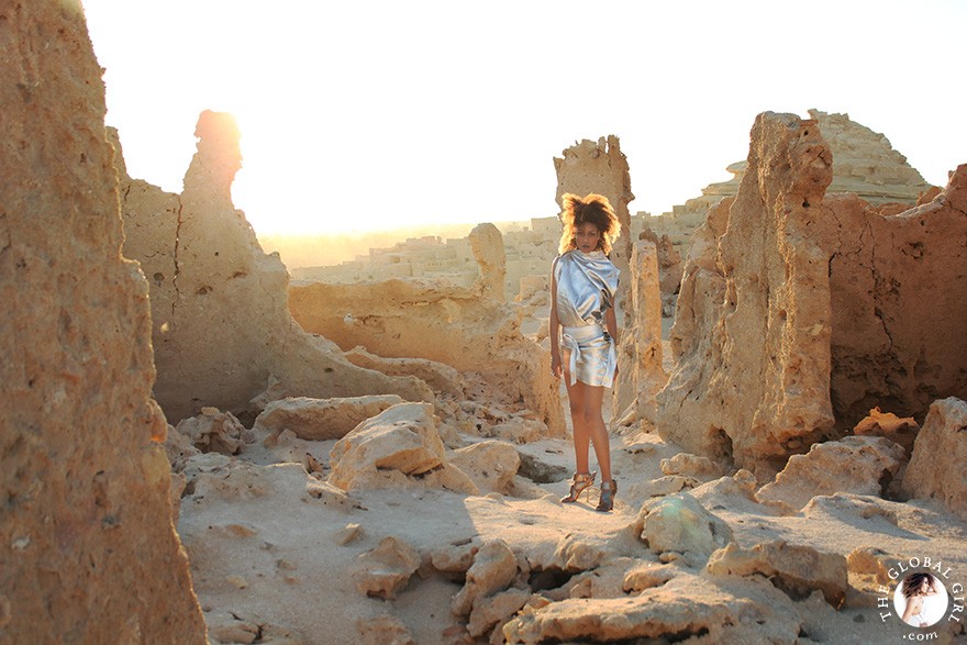 The Global Girl Fashion Editorials: Ndoema goes futuristic in a silver metallic dress against the ancient ruins of Shali Ghadi, a spectacular 13th-century fortress at Siwa Oasis, Egypt.