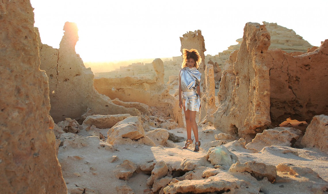 The Global Girl Fashion Editorials: Ndoema goes futuristic in a silver metallic dress against the ancient ruins of Shali Ghadi, a spectacular 13th-century fortress at Siwa Oasis, Egypt.