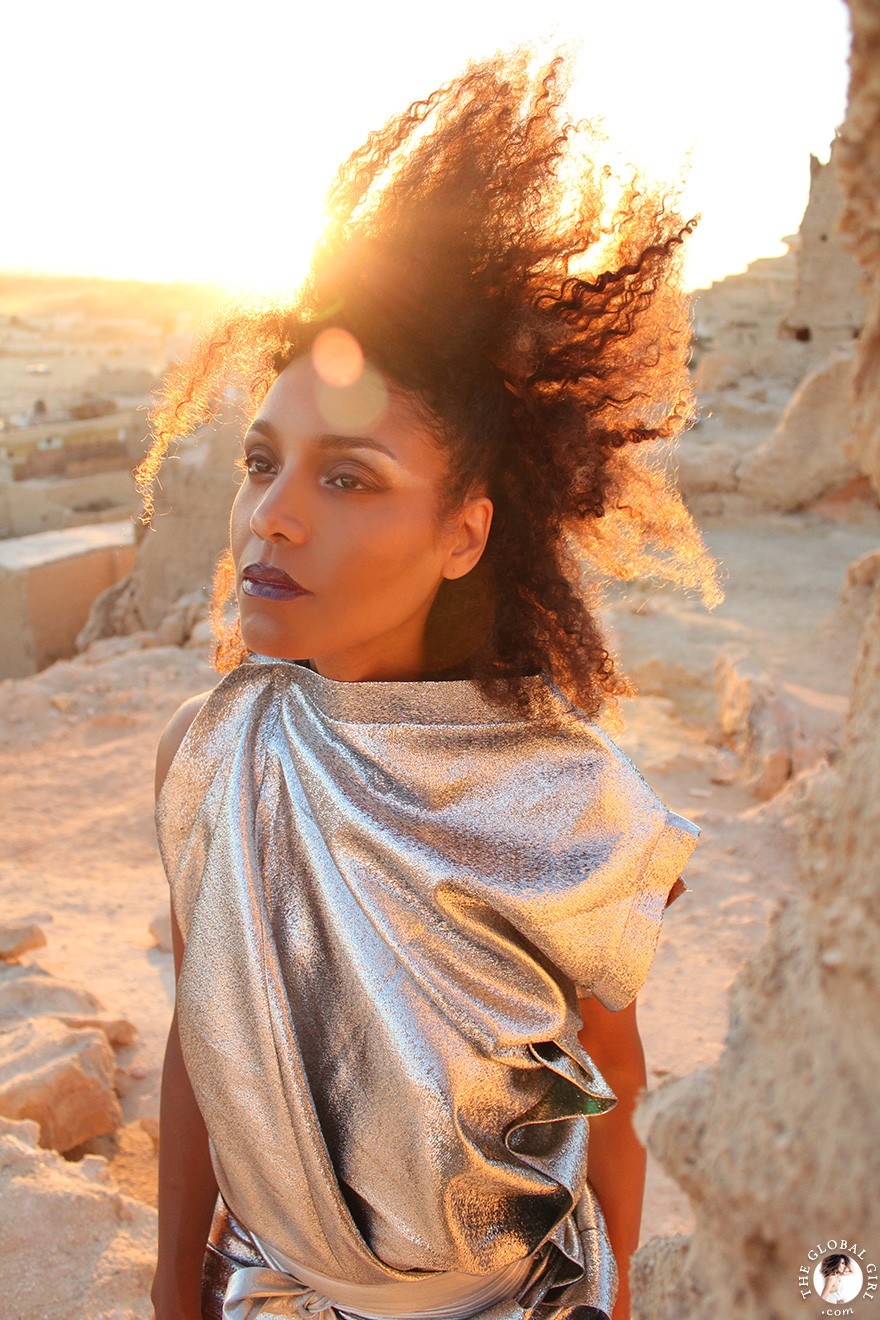 The Global Girl Fashion Editorials: Ndoema goes futuristic in a silver metallic dress against the ancient ruins of Shali Ghadi, a spectacular 13th-century fortress at Siwa Oasis, Egypt. 