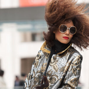 The Global Girl: Ndoema stars in a fashion editorial photographed by Paris-based photographer Kamel Lahmadi of Style and the City. Ndoema wears sunglasses by The Guise Archives, vintage silver and gold brocade coat, vintage gold chain and patent leather purse, Betsey Johnson gold glitter platform pumps, vintage black leather gloves, H&M gold metallic pants and vintage wool and fur scarf.
